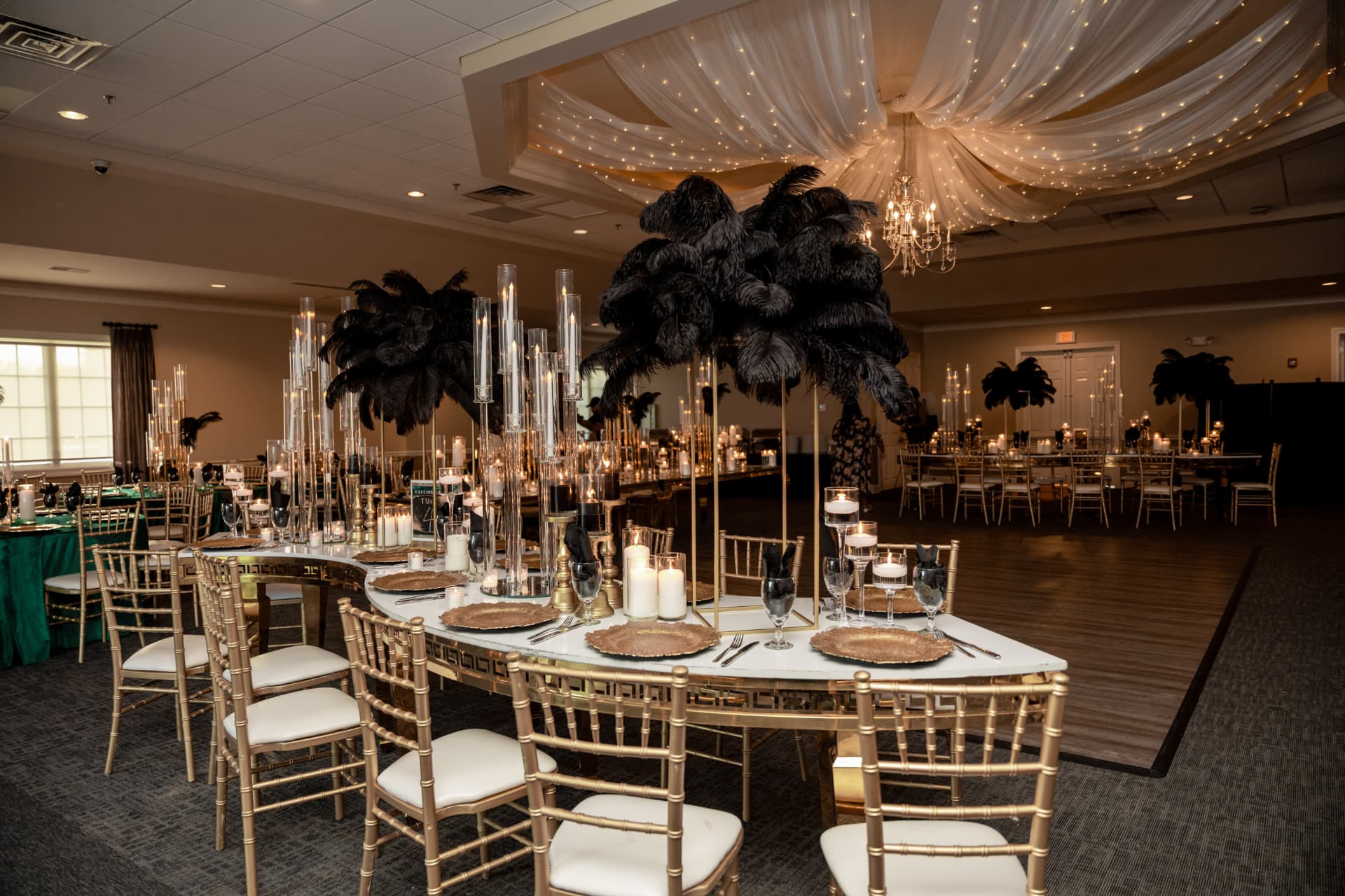 social event planner Chicago - elegant celebration with black feather centerpieces, gold chiavari chairs and candlelit tables under draped fairy lights